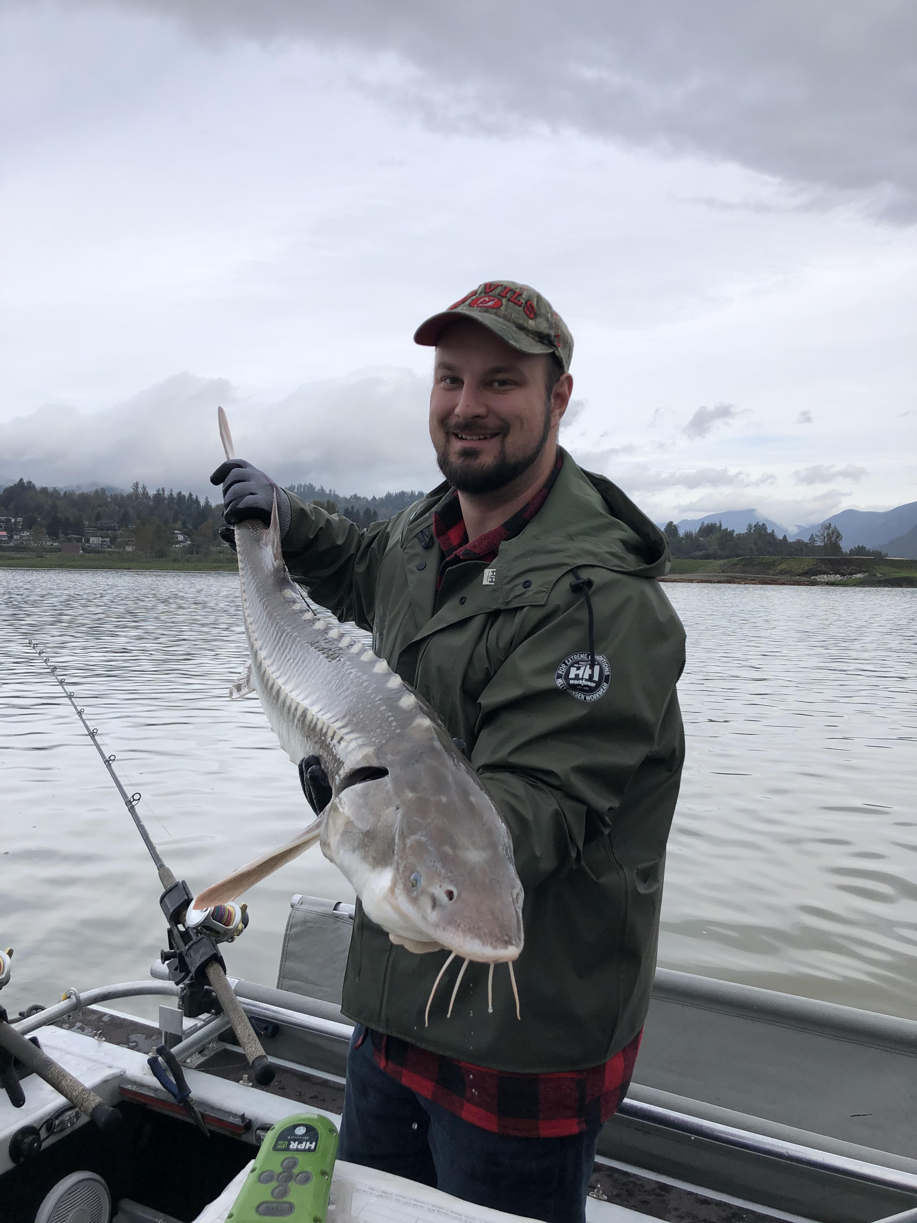 a man holding a juvenile sturgeon on a boat